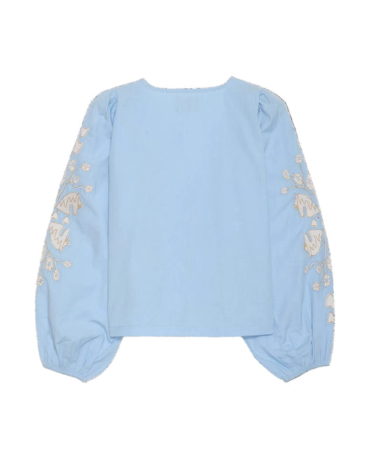 Light blue sweater with floral embroidery on sleeves against a black background