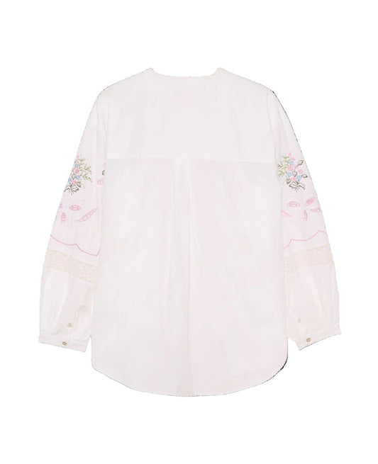 White blouse with floral embroidery on sleeves against a black background