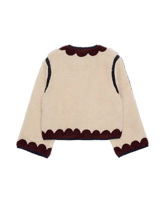 Beige sweater with brown scalloped edges on a black background